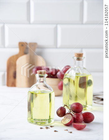 natural dietary and vegan grape seed oil in glass bottles on a white marble background. natural dietary and vegan grape seed oil in glass bottles on a white marble background. 114182057