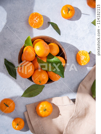 Flat lay sweet and juicy tangerines in a wooden bowl and a few tangerines on a blue background 114182115