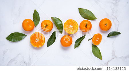 Flat lay sweet  tangerines and green leaves  on a white marble background. 114182123