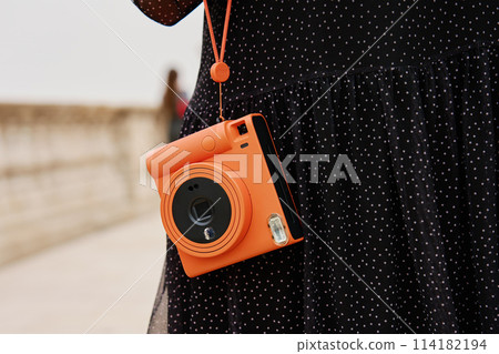 Female traveler holding vintage instant camera 114182194