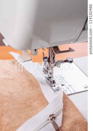 Modern sewing machine special presser foot with beige fabric and zipper, closeup 114182466