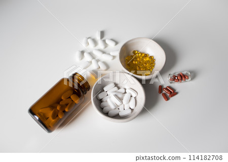 Many different pills and capsules on white background 114182708