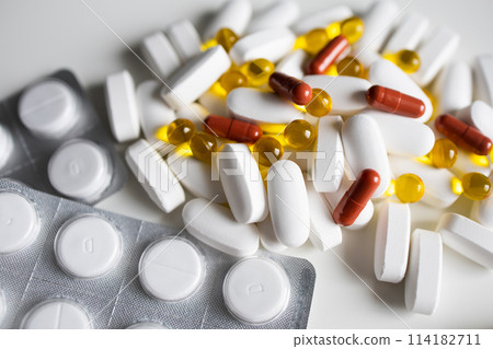 A pile of white and yellow pills and capsules and blistered tablets A pile of white and yellow pills and capsules and blistered tablets 114182711