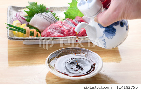 Pouring soy sauce with whale sashimi in the background 114182759
