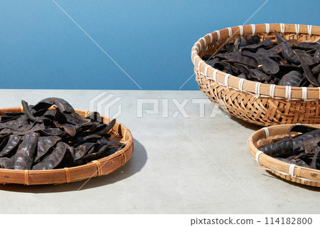 Several bamboo baskets containing a lot of black locust fruits inside arranged against blue background. Product that extracted from Black Locust can be displayed on the empty space Several bamboo baskets containing a lot of black locust fruits inside arranged against blue background. Product that extracted from Black Locust can be displayed on the empty space 114182800