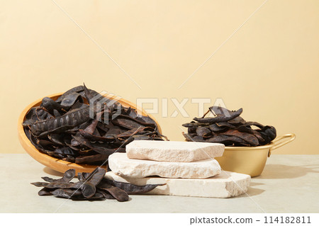 Front view of three stones stacked on each other. A lot of black locust fruits displayed. Black Locust (Fructus Gleditschiae) very useful for nurturing healthy, soft, and beautiful hair 114182811