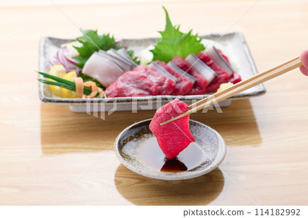 將小鬚鯨紅肉和真皮刺身沾上醬油。 114182992