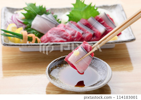 將小鬚鯨紅肉和真皮刺身沾上醬油。 114183001