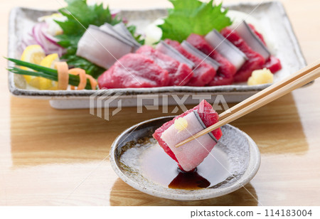 將小鬚鯨紅肉和真皮刺身沾上醬油。 114183004