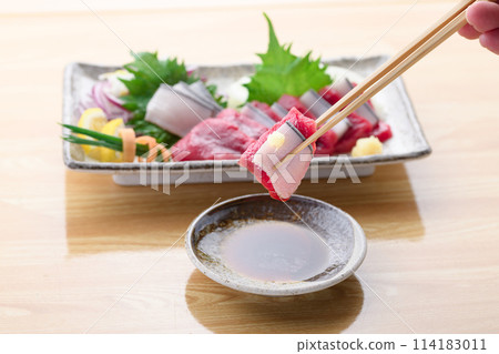 將小鬚鯨紅肉和真皮刺身沾上醬油。 114183011