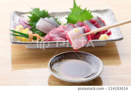 將小鬚鯨紅肉和真皮刺身沾上醬油。 114183014