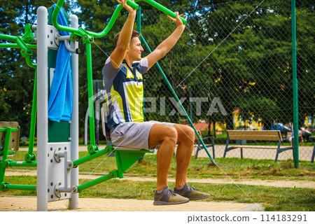 Man flexing arm in outdoor gym 114183291