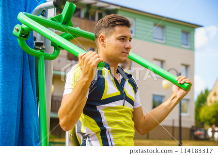 Man flexing arm in outdoor gym 114183317