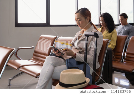 Asian female passenger with smartphone in airport terminale while waiting for her flight. Asian female passenger with smartphone in airport terminale while waiting for her flight. 114183796