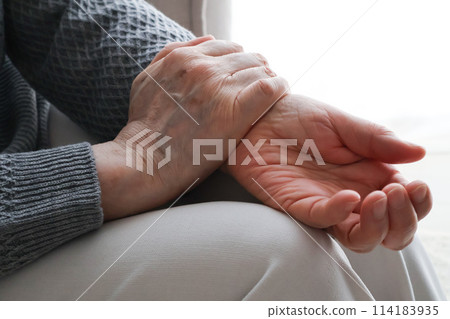Hands of an elderly woman grabbing her wrist Hands of an elderly woman grabbing her wrist 114183935