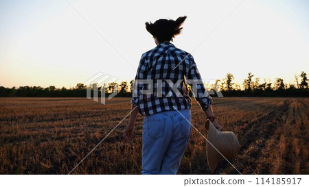 Female farmer running through the barley plantation at sunset. Agronomist jogging among wheat meadow at dusk. Beautiful scenic landscape. Concept of agricultural business. Close up Slow motion Female farmer running through the barley plantation at sunset. Agronomist jogging among wheat meadow at dusk. Beautiful scenic landscape. Concept of agricultural business. Close up Slow motion 114185917