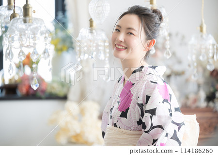 Close-up of a young Japanese (Asian) woman wearing a yukata with a beautiful sparkling background, looking at the camera Close-up of a young Japanese (Asian) woman wearing a yukata with a beautiful sparkling background, looking at the camera 114186260