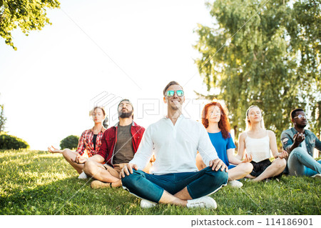 Group of adult mix-race friends meditating while practice yoga outside in park. Group of adult mix-race friends meditating while practice yoga outside in park. 114186901