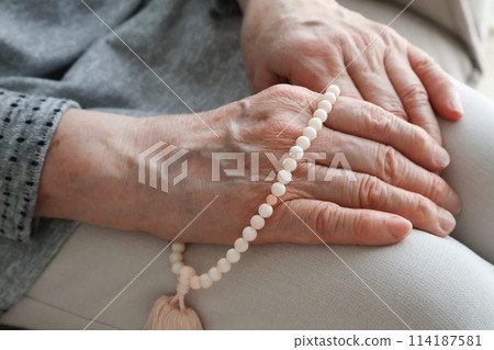 Senior woman's hands holding prayer beads 114187581