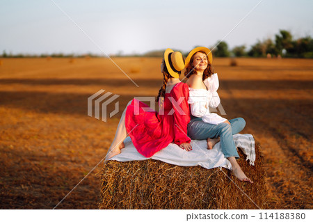 Two young women having fun near haystack. Fashion concept. Summer concept. 114188380