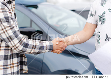 Man buying car and shaking hands with salesman against blurred auto, closeup. Concept of choosing and buying new car at showroom Man buying car and shaking hands with salesman against blurred auto, closeup. Concept of choosing and buying new car at showroom 114188545