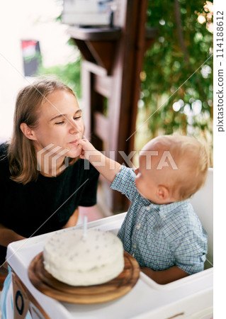 Little boy gives mom a taste of the cream from his fingers. High quality photo Little boy gives mom a taste of the cream from his fingers. High quality photo 114188612