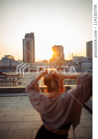 Beautiful woman standing on roof, feel happy at sunset. Freedom. Lifestyle, relaxation concept. 114188706