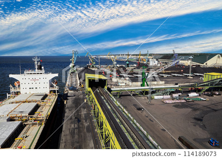 Coal Harbor and maritime bulk terminal with port cranes, coal embankments, bulk carriers at berth. Coal Harbor and maritime bulk terminal with port cranes, coal embankments, bulk carriers at berth. 114189073
