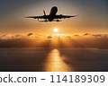 Sunrise over the sea and the silhouette of a jumbo jet 114189309