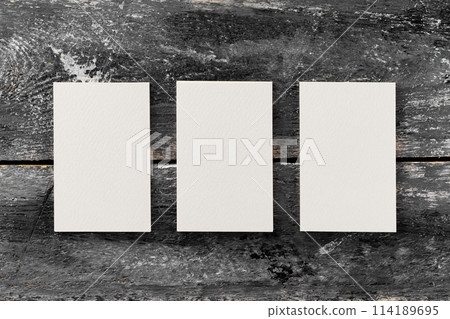 Top view mockup of three blank white business cards at vintage wooden table background. Top view mockup of three blank white business cards at vintage wooden table background. 114189695