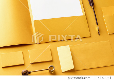 Corporate stationery set mockup. Presentation folder, letterhead, envelope and business cards at golden textured foil paper background. Corporate stationery set mockup. Presentation folder, letterhead, envelope and business cards at golden textured foil paper background. 114189981