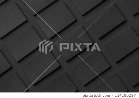 Mockup of horizontal business cards stacks arranged in rows at black textured paper background. 114190287