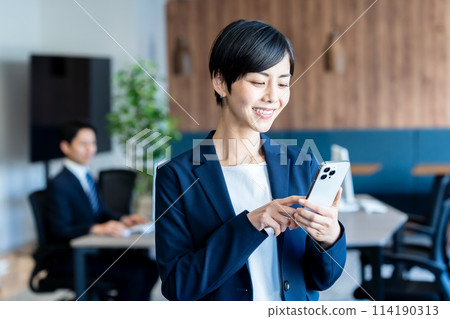 Business woman with a smartphone in the office Business woman with a smartphone in the office 114190313