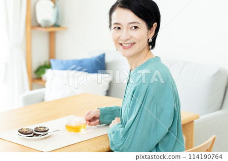 中年婦女在客廳喝花草茶 中年婦女在客廳喝花草茶 114190764