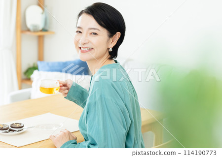 Middle-aged woman drinking herbal tea in the living room 114190773