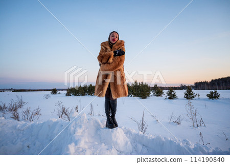 A beautiful girl in a fur coat walks and has fun in the winter forest A beautiful girl in a fur coat walks and has fun in the winter forest 114190840