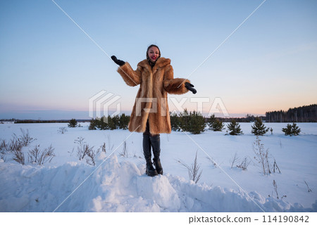 A beautiful girl in a fur coat walks and has fun in the winter forest A beautiful girl in a fur coat walks and has fun in the winter forest 114190842