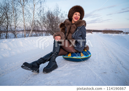 a beautiful girl in a fur jacket and hat walks and has fun in the winter forest. a beautiful girl in a fur jacket and hat walks and has fun in the winter forest. 114190867