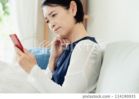 使用智能手機的婦女在客廳 使用智能手機的婦女在客廳 114190935