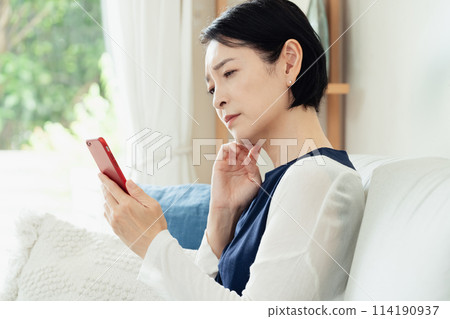 A woman using a smartphone in the living room 114190937