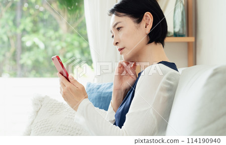 使用智能手機的婦女在客廳 114190940