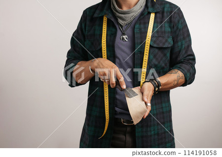 Cropped image of a shoemaker with measure tape and tools 114191058