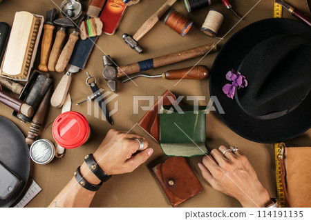 Leather goods master and handmade leather wallets. Workflow in the workshop. Leather goods master and handmade leather wallets. Workflow in the workshop. 114191135