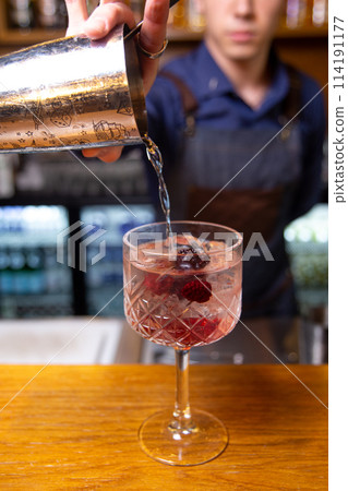Bartender prepares a cocktail with berries at the bar. Bartender prepares a cocktail with berries at the bar. 114191177