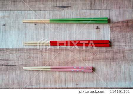 A family of three, parents, daughter, all use chopsticks of different colors. 114191301