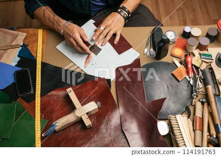 Close up of skinner craftsman working with natural leather using craft tools. Close up of skinner craftsman working with natural leather using craft tools. 114191763