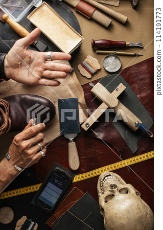 Close up of shoe maker hands producing boots in his leather workshop 114191773