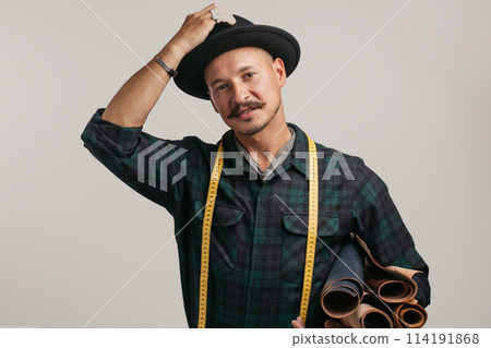 Artisan of leather in creative black hat posing with leather goods in studio. 114191868