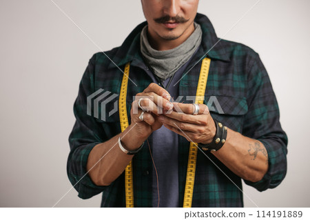 Cropped image of a shoemaker with measure tape and tools 114191889