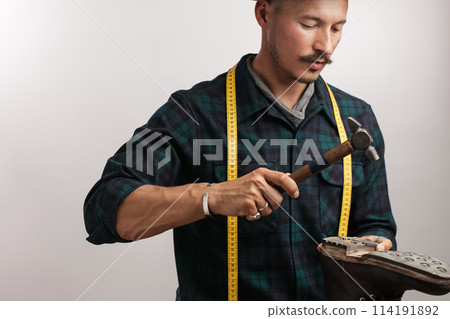 Cropped image of a shoemaker measuring a shoe with measure tape in workshop 114191892